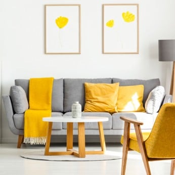 Wohnzimmer mit einem Grauen Sofa und gelber Dekoration
