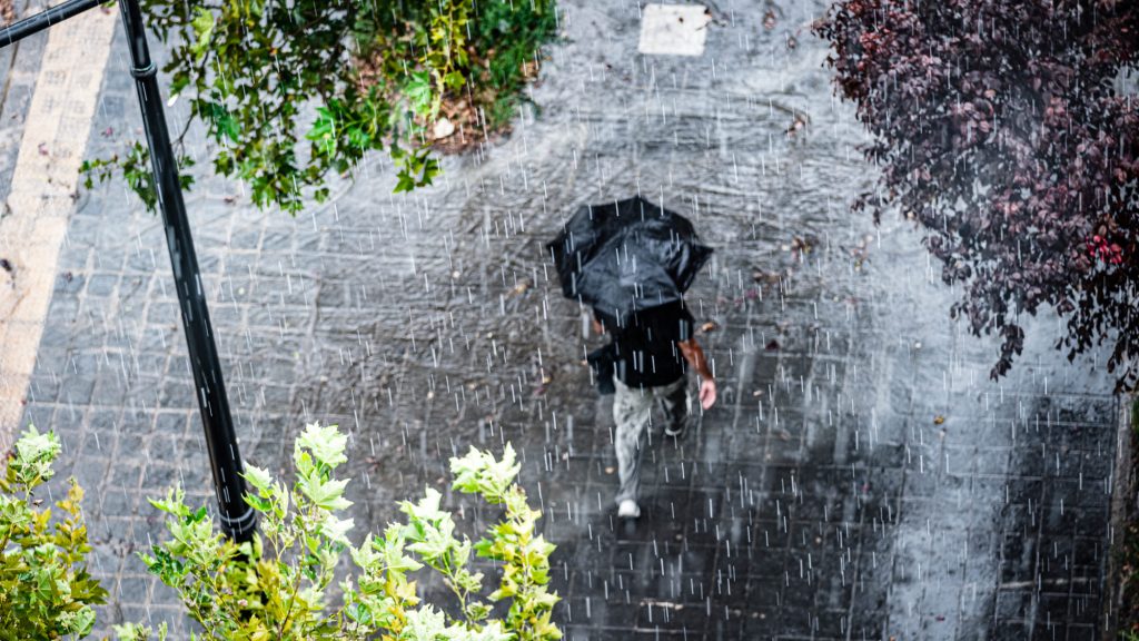 Mensch im Regen mit Regenschirm von oben