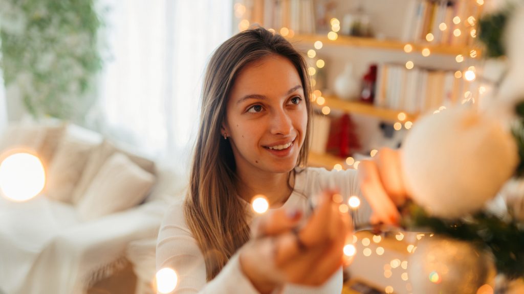 Eine Frau schmückt einen Weihnachtsbaum mit Kugeln